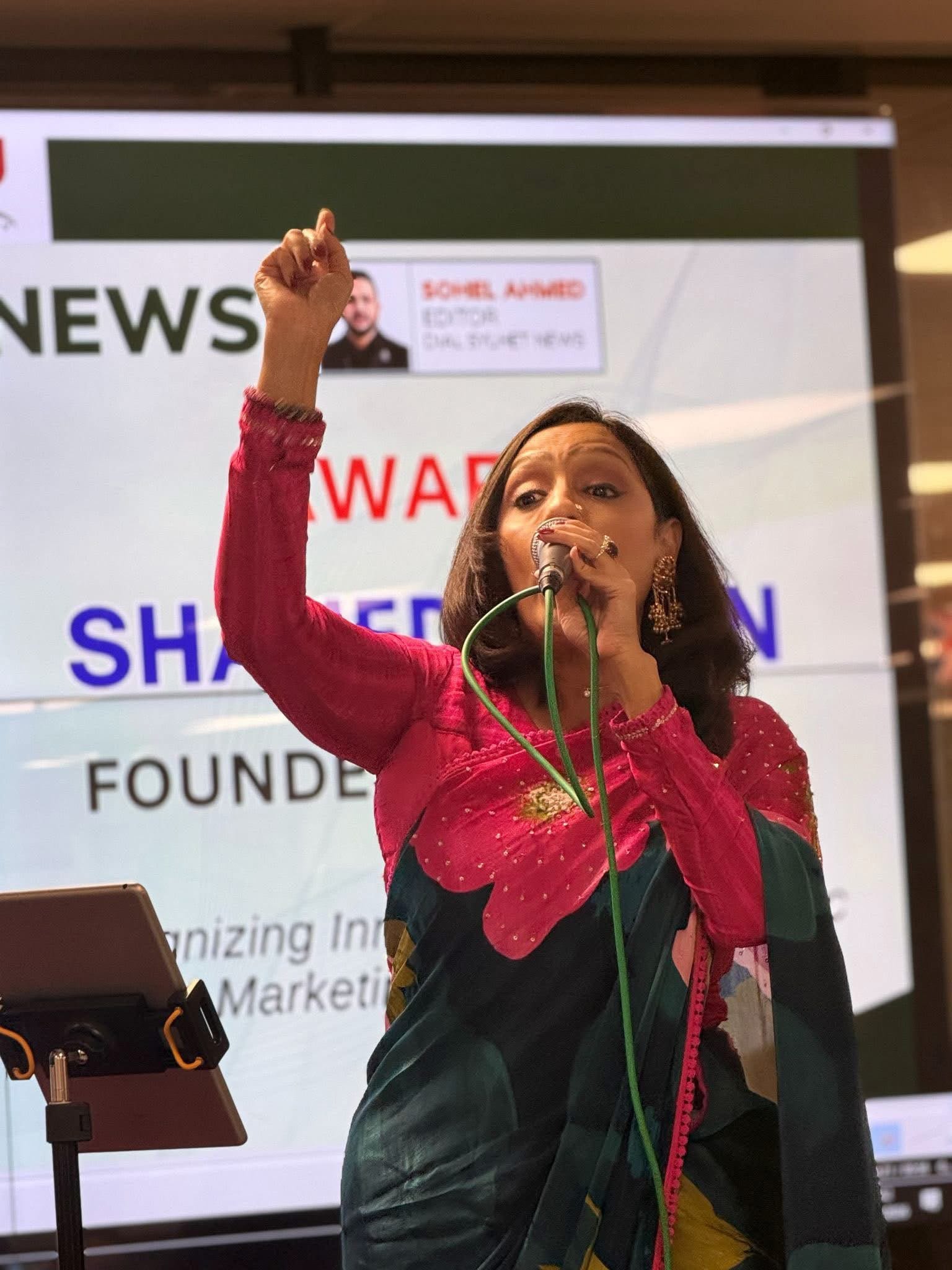 Rowshanara Moni singing with one arm raised at the Dial Sylhet 8th anniversary celebration in London