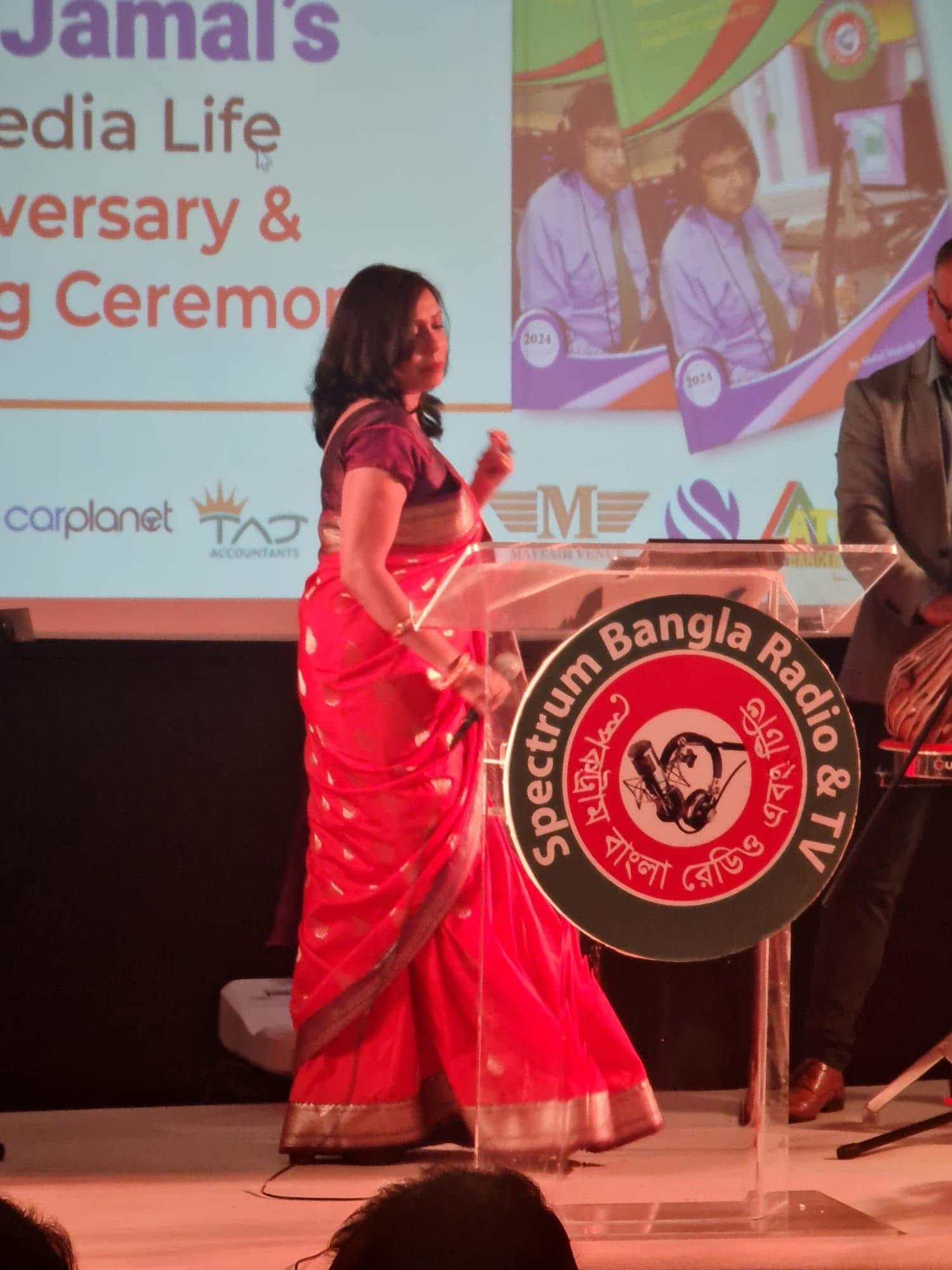 Rowshanara Moni speaking at a lectern bearing the Spectrum Bangla Radio and TV emblem